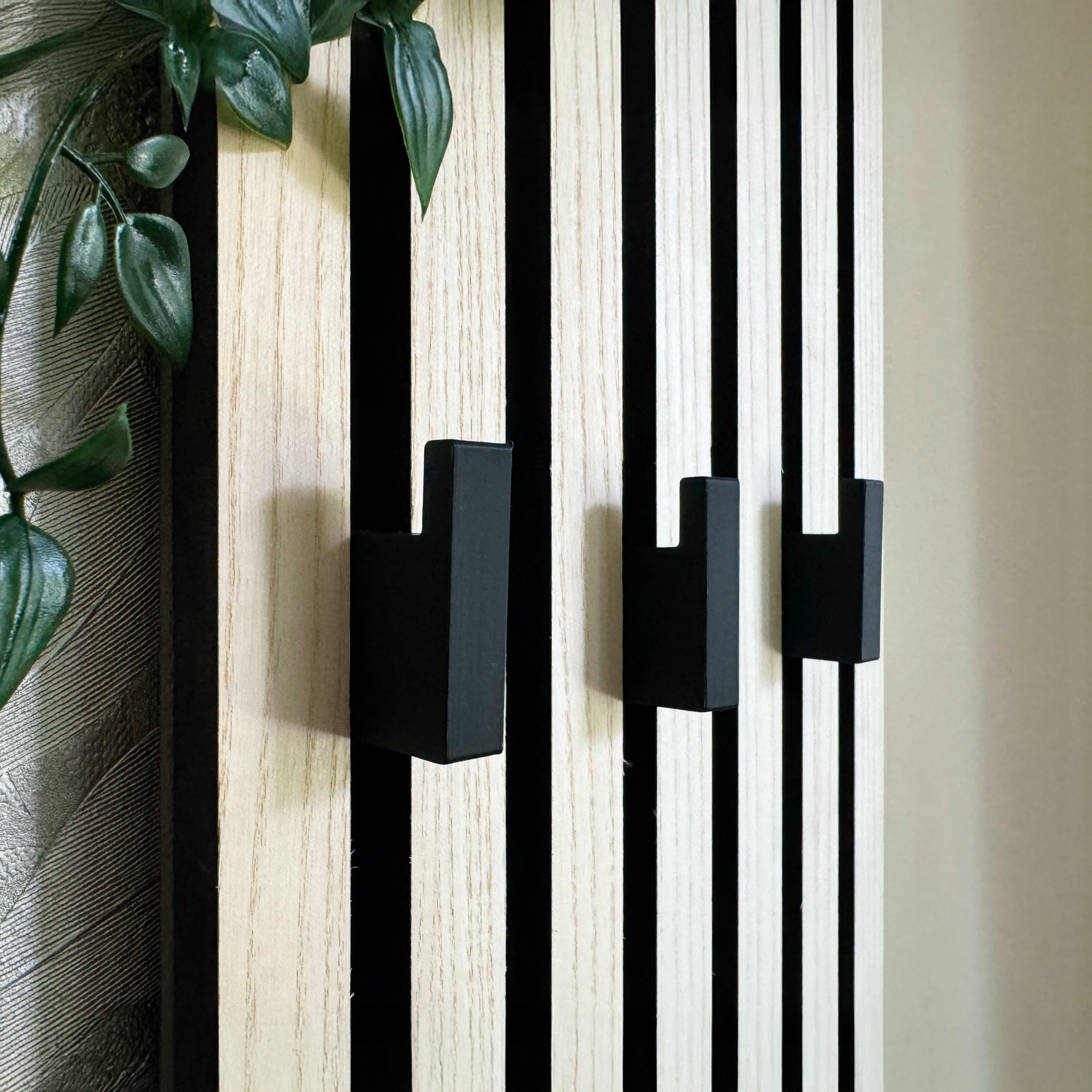 Eleganter Haken an Akustikpaneel zur platzsparenden und ästhetischen Umwandlung in eine Garderobe für Mäntel, Taschen und Accessoires in Büro- und Wohnräumen.