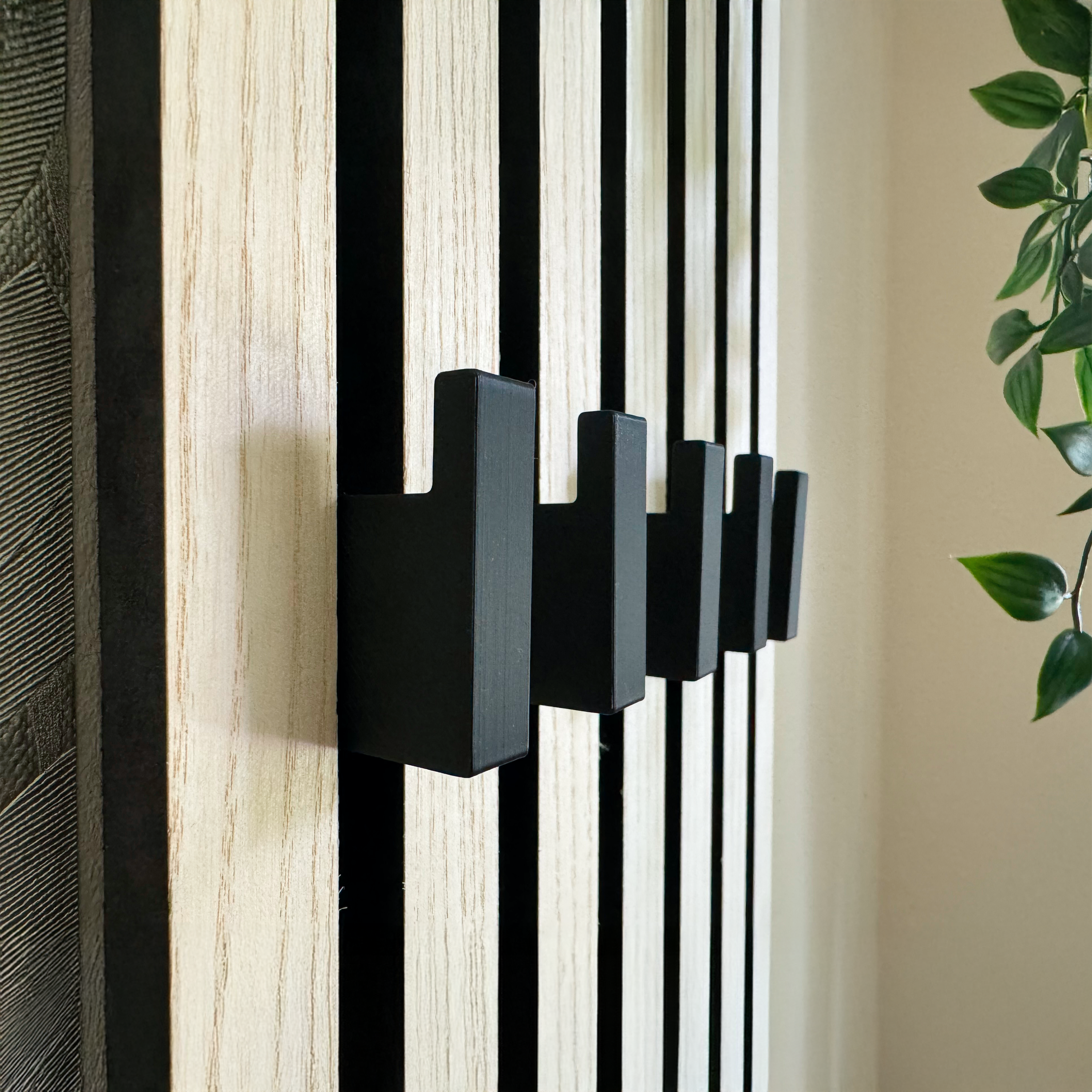 Eleganter Haken an Akustikpaneel zur platzsparenden und ästhetischen Umwandlung in eine Garderobe für Mäntel, Taschen und Accessoires in Büro- und Wohnräumen.