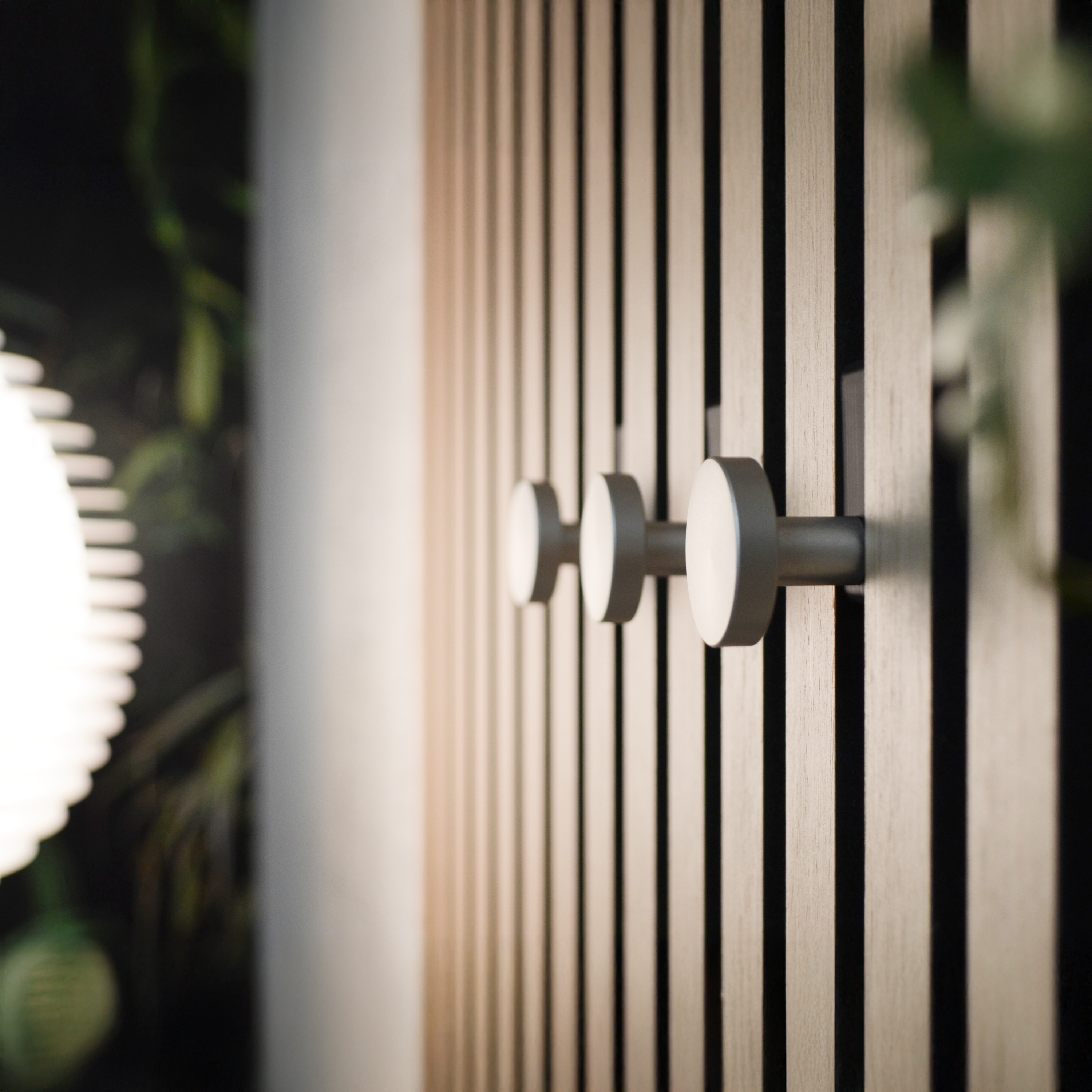 Modernes Wandpaneel mit vertikalen Holz- und schwarzen Akustikstreifen, ausgestattet mit stilvollen silbernen Wandhaken. Hochwertiges Akustikpaneel Zubehör für eine elegante Garderobe mit bohrfreier Montage. Ideal für Flur, Eingangsbereich oder Schlafzimmer.