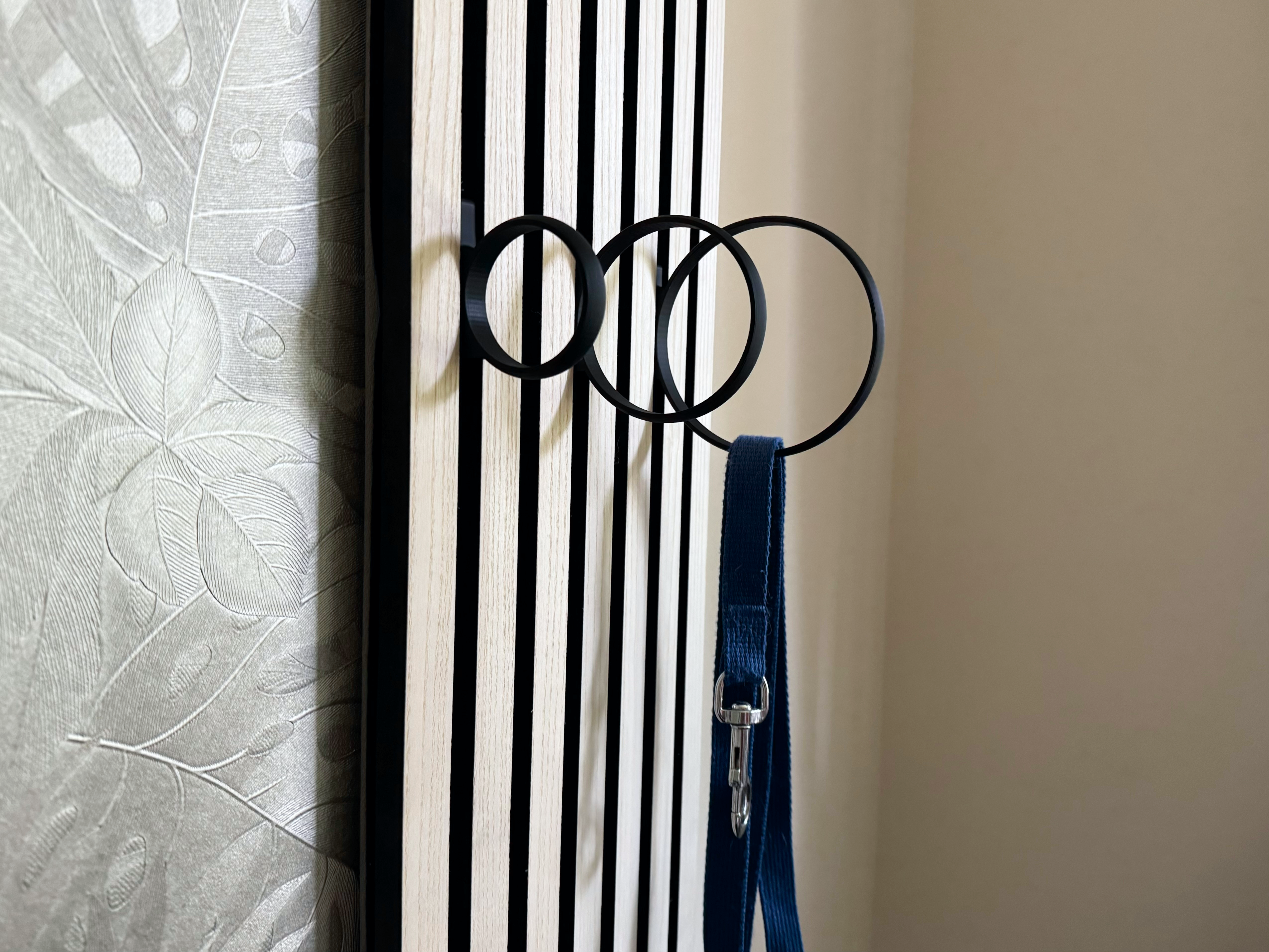 Eleganter Haken an Akustikpaneel, der das Paneel in eine platzsparende und ästhetische Garderobe für Schals, Leinen und Accessoires von Hund und Katze in Büro- und Wohnräumen verwandelt.