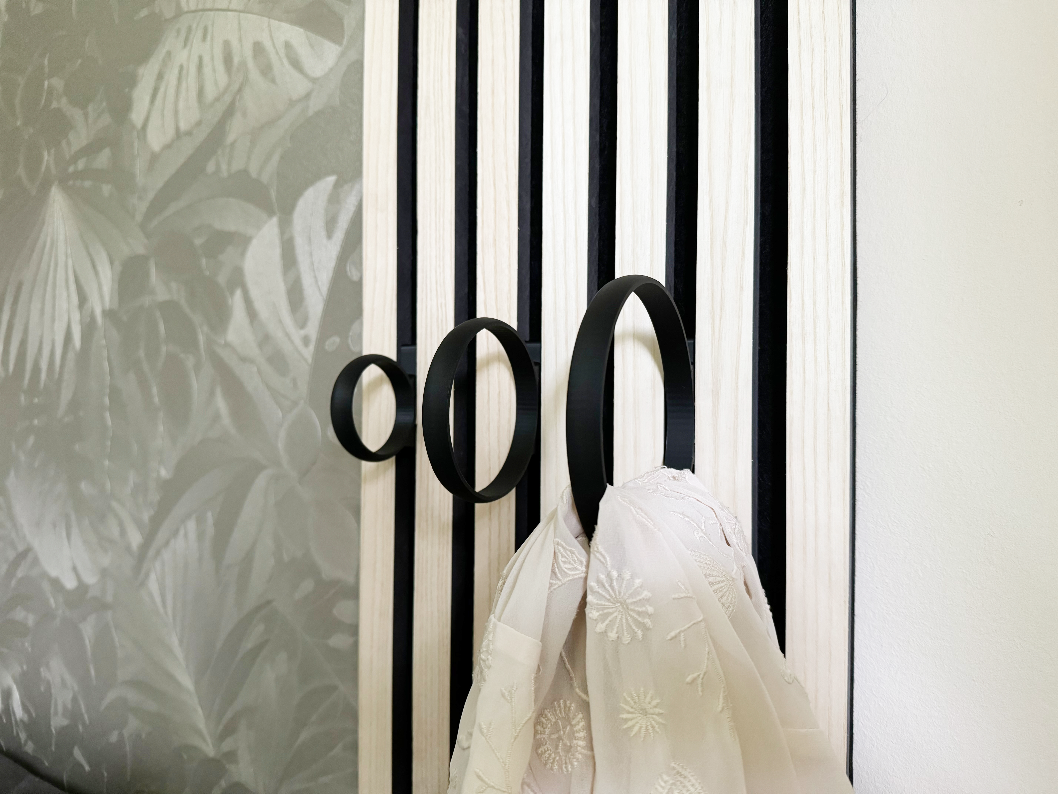 Eleganter Haken an Akustikpaneel, der das Paneel in eine platzsparende und ästhetische Garderobe für Schals, Leinen und Accessoires von Hund und Katze in Büro- und Wohnräumen verwandelt.